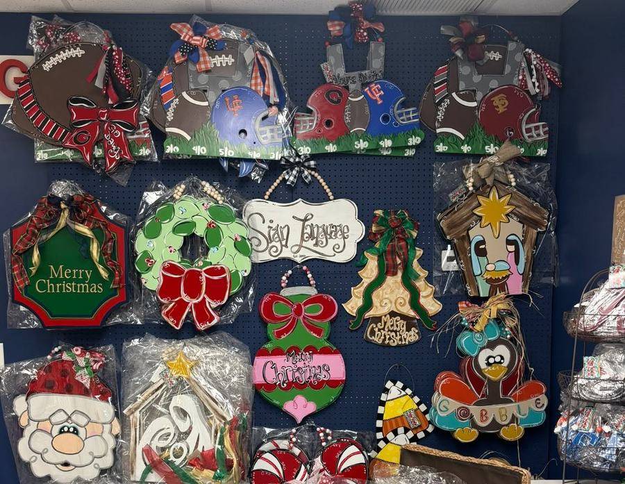 A wall of hand-painted wooden door hangers at Waas Drug Store, including game-day, Christmas and Thanksgiving designs
