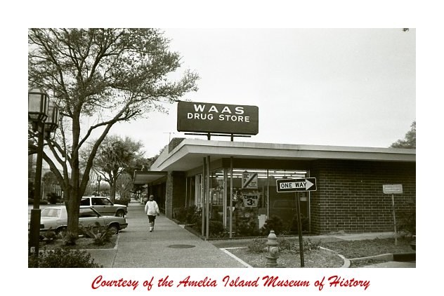 The WAAS DRUG STORE sign standing above the roofline at 515 Centre Street,
                  a pedestrian walking up the sidewalk on a winter day