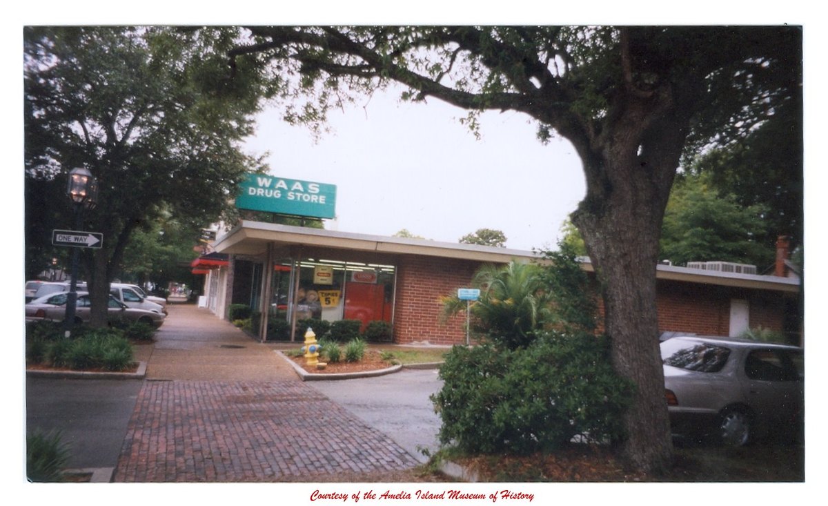 The WAAS DRUG STORE on Centre Street, a low brick mid-century building with a teal
                  sign, photographed in the 1990s