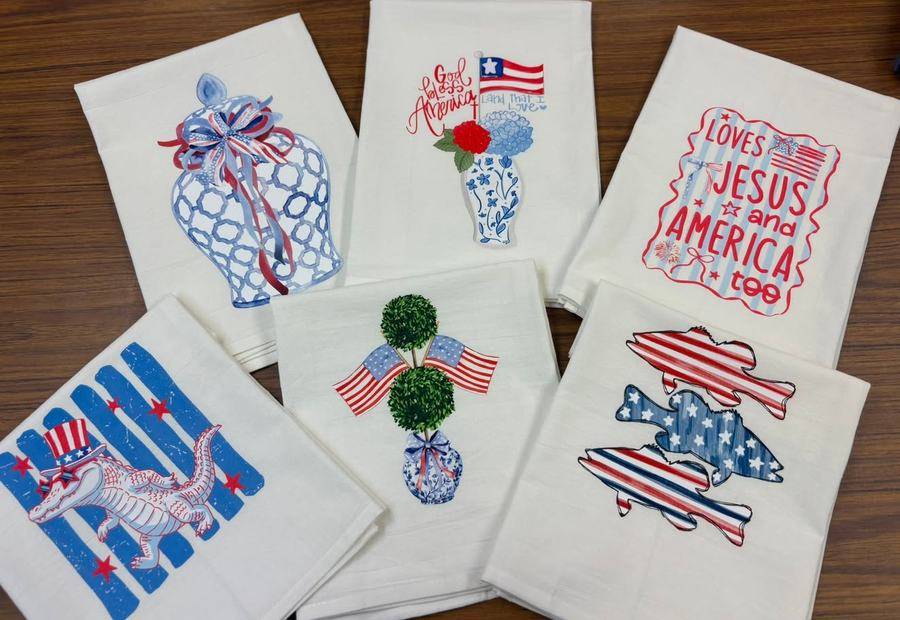 Cotton tea towels with patriotic, coastal fishing, gator and floral designs, fanned out on a table